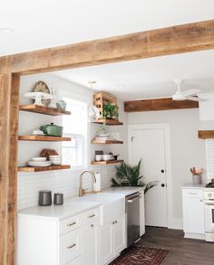 a white kitchen with open shelving above the sink