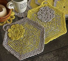 there is a coffee cup on the table next to some crocheted coasters