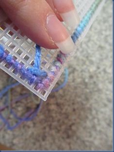 a person holding a piece of plastic with yarn on it