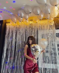 a woman in a red dress holding balloons