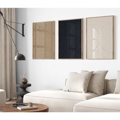 a living room with white couches and two framed pictures on the wall above them