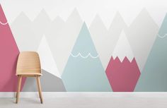 a chair sitting in front of a wall with mountains painted on it's sides