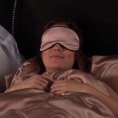 a woman laying in bed with blindfold on her head