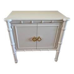 a white cabinet with gold handles on the front and bottom drawers, against a white background