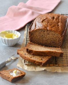 a loaf of bread sitting on top of a cooling rack next to a bowl of butter