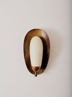 a wall light mounted on the side of a white wall next to a wooden frame