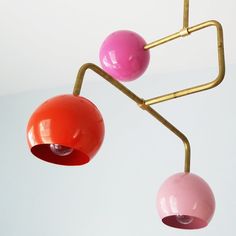 two pink and one orange balls hanging from a metal rod