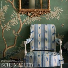 a blue and white chair sitting in front of a wall with a mirror on it