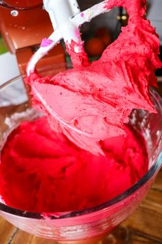 a mixer is mixing red food in a bowl