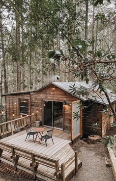 a small wooden cabin in the woods with lights on it's roof and deck