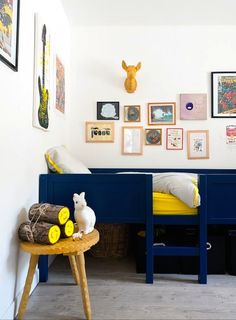 a room with two beds and some pictures on the wall above them, along with a small wooden stool