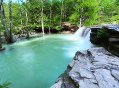 there is a small waterfall in the middle of this river that has blue green water