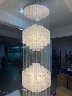 a chandelier made out of white flowers in a room with boxes on the floor