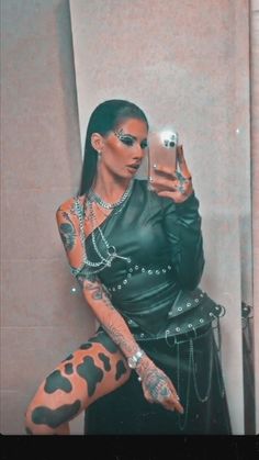 a woman with tattoos is taking a selfie in the mirror while holding a cell phone