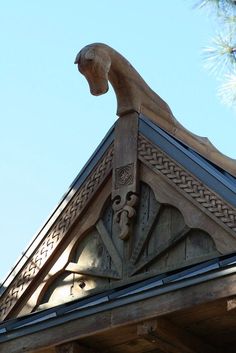 the top of a building with a gargoyle on it's roof and a pine tree in the background