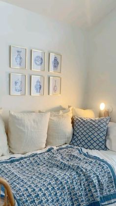 a bed with white pillows and blue blankets in a room next to pictures on the wall