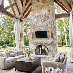 an outdoor living room with stone fireplace and couches