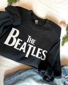 the beatles t - shirt and jeans are laying on top of a bed with ivy