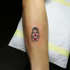 a woman's arm with a small tattoo of a matkabell doll on it