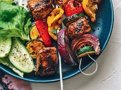 a blue plate topped with meat and veggies on top of a bed of lettuce