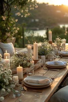 an outdoor table set for dinner with candles and flowers on the table, along with other place settings