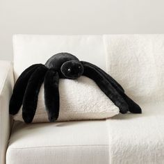 a stuffed spider sitting on top of a white couch next to a black and white pillow