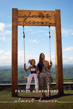 two women sitting on a swing in front of a sign that says almost heaven, family adventure almost heaven