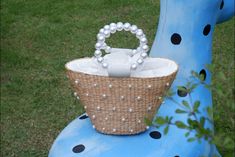 a wicker basket sitting on top of a blue chair with pearls in the handle