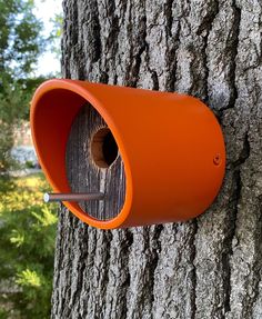 an orange bird house attached to a tree