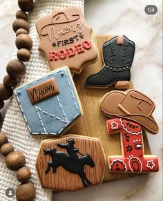 decorated cookies with cowboy themed decorations on a wooden board and bead necklace, along with beads