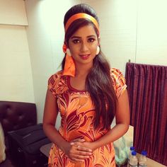 a woman standing in front of a table with food on it and wearing an orange dress