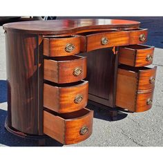 a wooden desk with several drawers on it's sides and one drawer open to show the contents