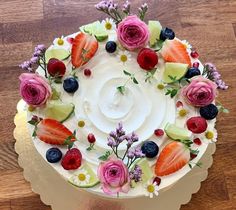 there is a cake decorated with flowers and fruits on the top layer, as well as berries and cucumbers