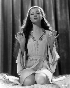 a woman sitting on top of a bed with her hands in the air