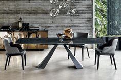 a dining table with chairs around it in front of a brick wall and glass chandelier