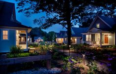 a row of houses lit up at night with lights shining on the front and side