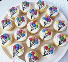 cupcakes with white frosting and colorful balloons on them are arranged in a circle