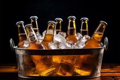 six bottles of beer in a bucket with ice cubes on a wooden table and black background