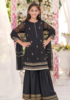 3- Piece Embroidered Suit for Girls A serene jet black chiffon shirt with an attached malai crepe lining beautifully highlighted with gold block print, the gold sequin craftsmanship on the front button placket brings out a touch of glamour as it is paired with a black raw silk block printed gharara and a black chiffon dupatta with touches of gold laces. This elegant attire is sure to be a show stopper at any formal gathering this season ! Top: Black Chiffon Kurta with Hand Adda Work Placket and Chiffon Gharara, Chiffon Kurta, Silk Gharara, Gharara Dress, Black Chiffon Shirt, Asian Designers, Kurta Dress, Elegant Attire, Chiffon Dupatta