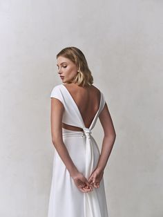 a woman in a white dress is standing with her back to the camera and looking down