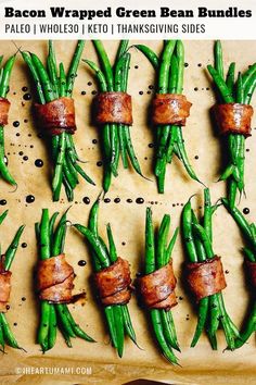 green beans wrapped in bacon are arranged on a sheet of parchment paper and ready to be cooked