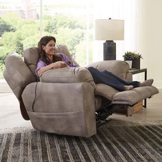 a woman sitting in a recliner with her feet up on the back of it