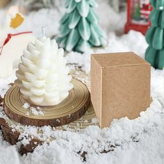 a white candle sitting on top of a piece of wood next to a cardboard box