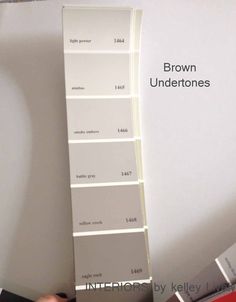 a person is holding a paint swatch in front of a wall with the words brown undertones on it