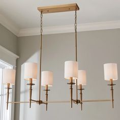 a chandelier hanging from the ceiling in a living room with white walls and windows