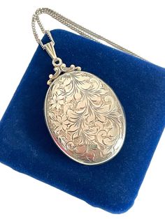 Description: Beautiful and large, the signature Birks style vintage oval locket, hand engraved with a whimsical swirling leaves and flower design, crowned with a fancy filigree top.  The sterling silver pendant opens easily and holds two oval areas for photos.  The design is on the front of the locket.  The back has a monogram engraving. It reads "IH" in cursive (open for interpretation - could also be JH or TH).   The locket hangs from a triangular grooved bail.  Hangs on a lovely, long and shiny silver link chain (24'' long). The photo frames are intact and in very good vintage condition.  Measures:  Chain: Approx. 22'' long. Locket (Oval Only): 1 7/8'' (Includes fancy filigree top) and 1 3/16'' wide. Weighs:   - 22.1 grams (locket with chain) Condition: In nice vintage condition.  Clasp Sterling Silver Locket Necklace, Locket Necklace Vintage, Silver Locket Necklace, Silver Link Chain, Sterling Silver Locket, Oval Locket, Silver Locket, Flower Leaves, Photo Pendant