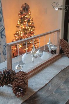 a christmas tree is in the background with pine cones and other decorations on a table