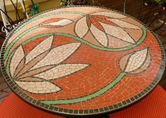 a mosaic table with orange and green leaves on it