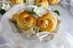 two little pigs in a basket with white flowers on the table next to other small ones