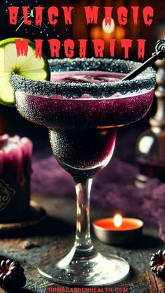 a close up of a drink in a glass on a table with a candle behind it